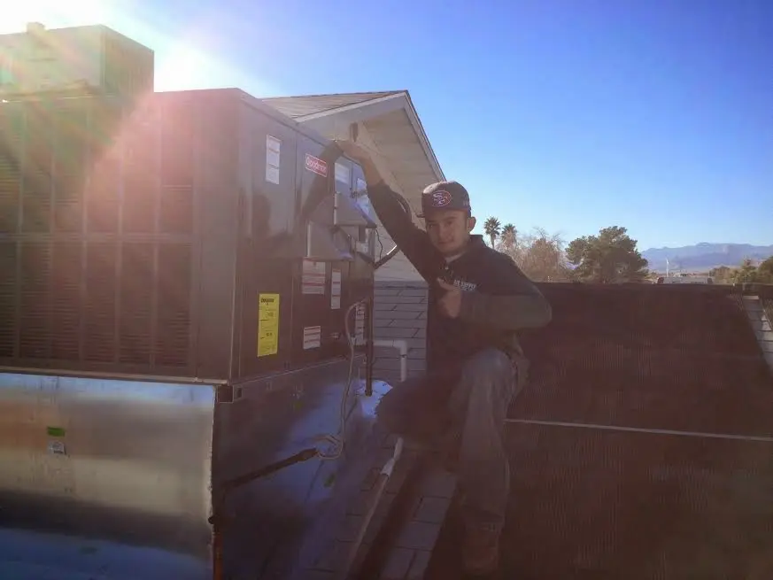 HVAC technician performing Boiler Repair on a rooftop unit in Grosse Ile